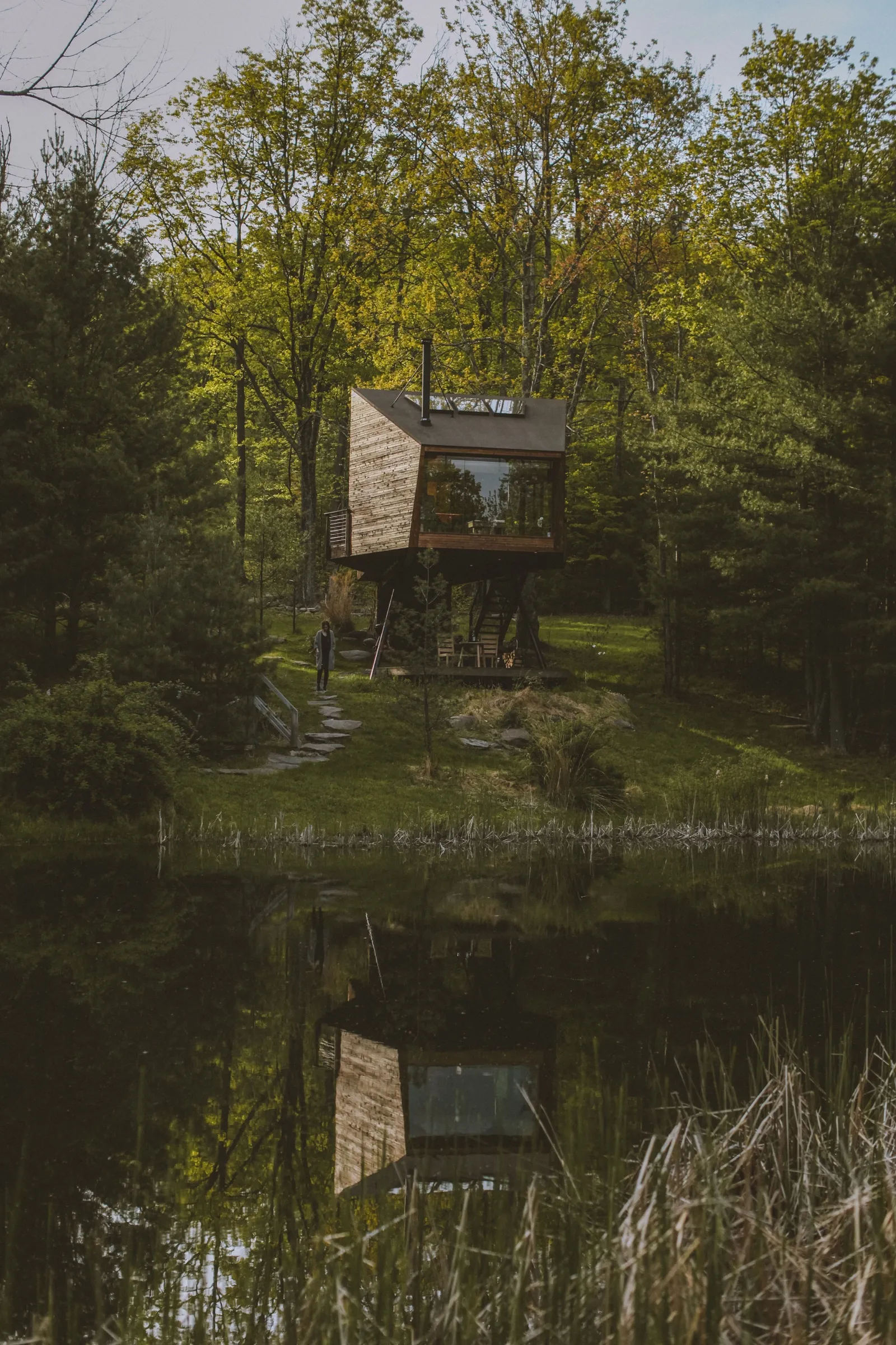 Willow Treehouse reflected in the pond on a spring day